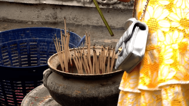 Tourist putting a smoky incense stick into a brazier