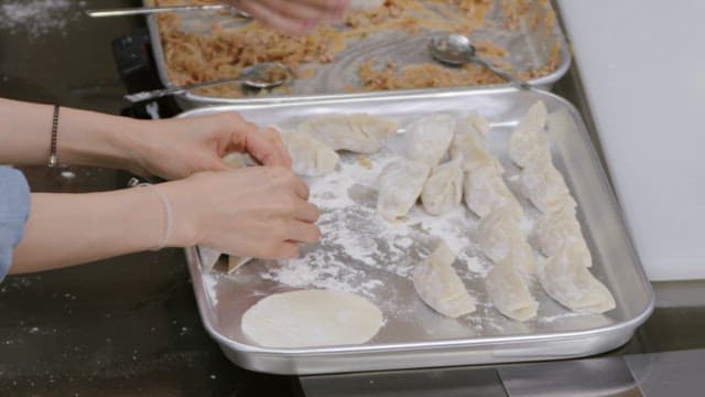 Putting beautifully made dumplings on a tray in the kitchen