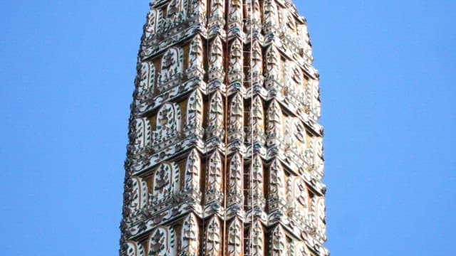 Colorful decorations on the exterior walls of Thai temple spires under a blue sky