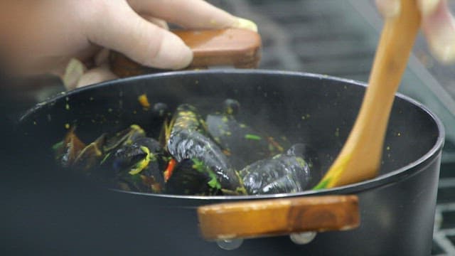 Mussels being cooked with spatula in a pot