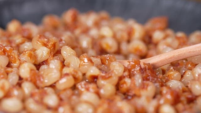 Scooping Fried Corn in a Frying Pan with a Wooden Spoon