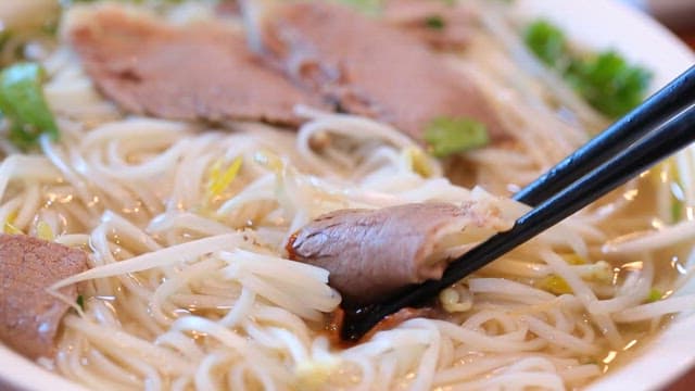 Chopstickful of rice noodles with beef slices