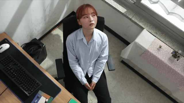 Woman sitting in office, looking contemplative.