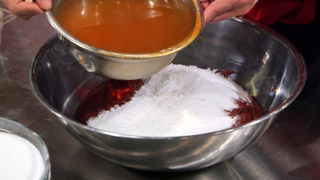 Pouring the broth into a large bowl with sugar and gochujang