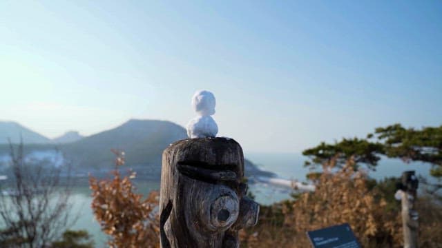 Coastal Scenery Behind Snowman and Tree Sculpture