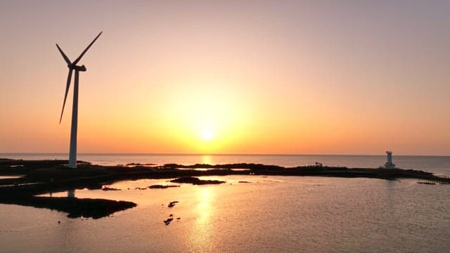 Sunset over the ocean with a wind turbine