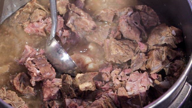 Cooked pork backbones in a ladle