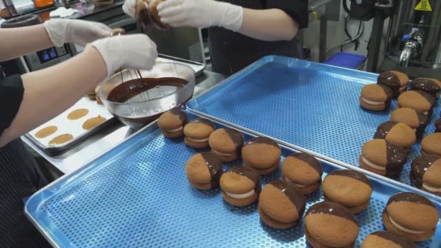 Chocolate coated cookies being placed on a tray