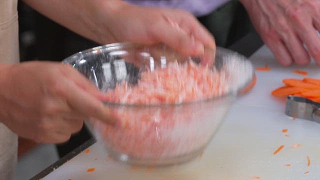 Mixing Carrots and Flour in a Glass Bowl to Make Batter
