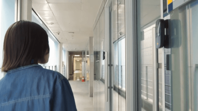 Woman walking down a bright hallway