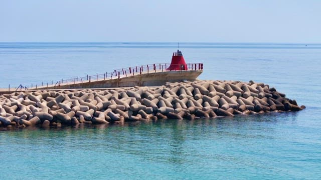 Breakwater with a red lighthouse by the sea