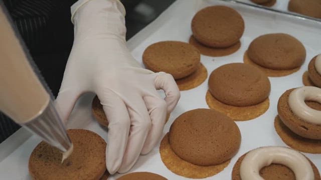 Piping cream onto freshly baked cookies in a bakery