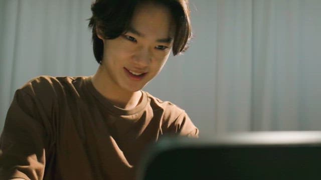 Young man smiling while using a laptop