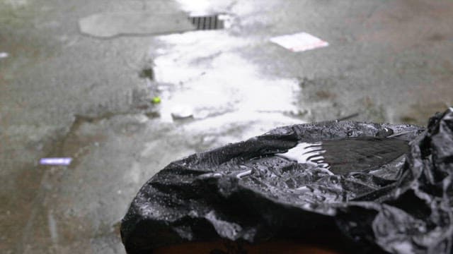 Puddle forming on a black plastic bag in rainy day