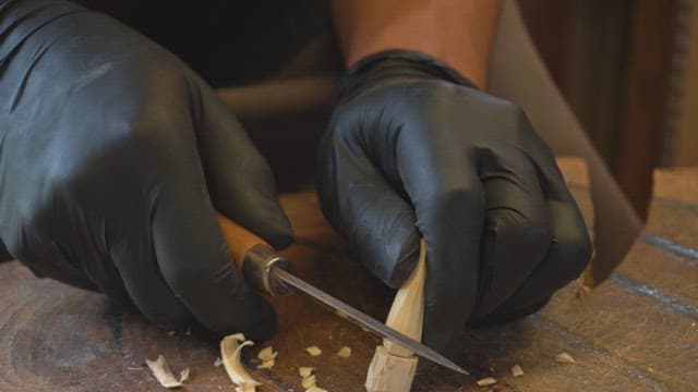 Hands carving wood with a knife