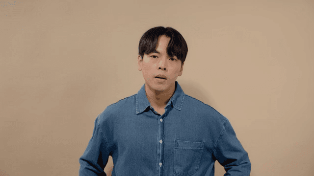 Man in a denim shirt looking straight ahead with a serious expression