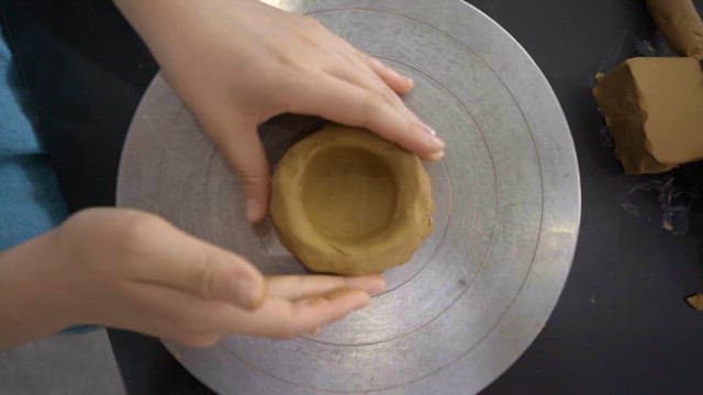 Hands shaping pottery on a potter's wheel