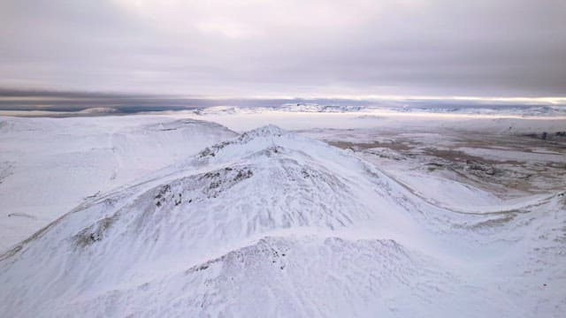 Snow-covered mountain range under cloudy sky