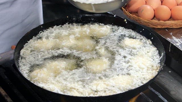 Batter being poured into hot oil for frying