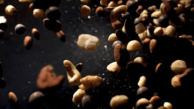 Various types of nuts bouncing on a black background