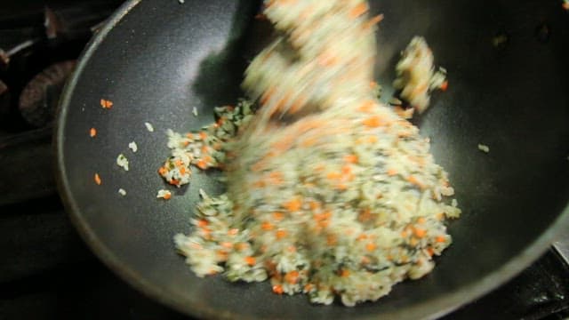 Fried rice with crab innards and chopped vegetables in a frying pan