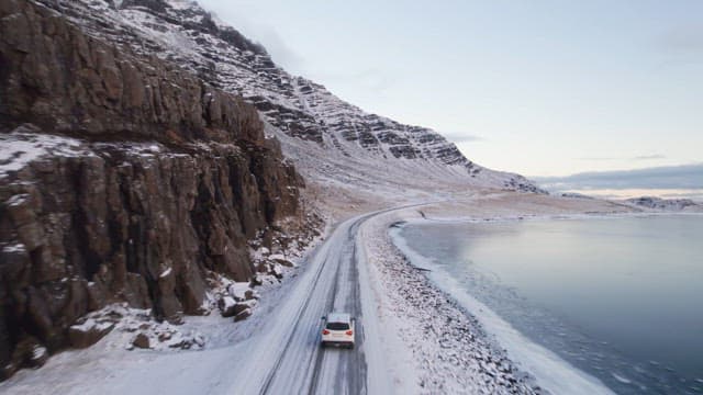 Car driving on a snowy coastal road