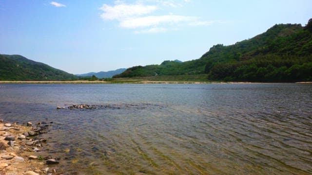 Serene riverside and green mountain landscape on a clear day