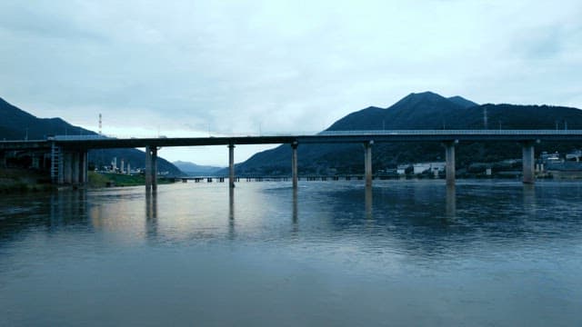 Calm river with a view of the bridge and mountains