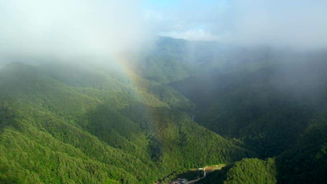 Scenic View of Foggy Mountains with a Faint Rainbow