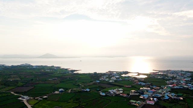 Coastal village with farmland and sunlight over the sea