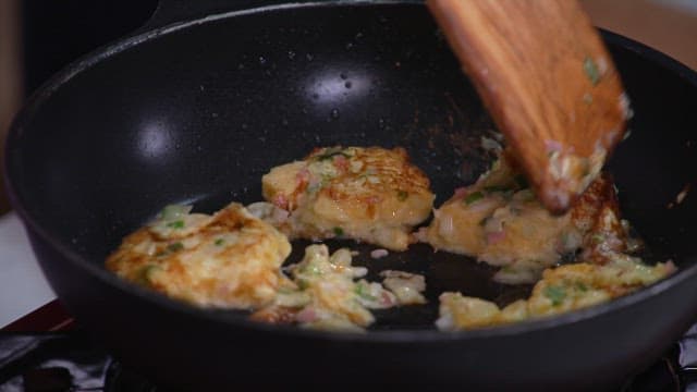 Cooking slices of bread coated with green onion and egg mixture in a frying pan