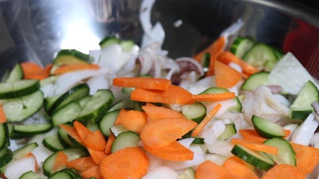 Mixing fresh vegetables with spicy sauce in a bowl