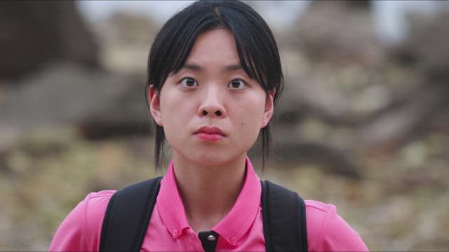 Woman standing in the forest wearing pink clothes and carrying a bag