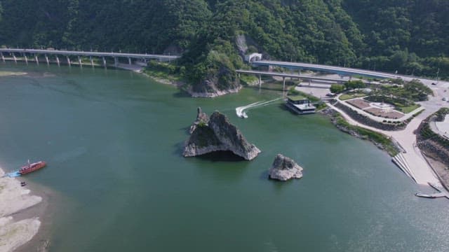 Yacht Swiftly Passing a Large Rock on the River