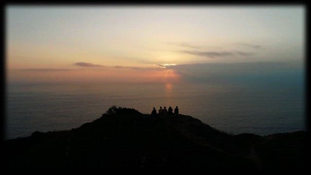 Silhouettes of people watching sunset over the ocean