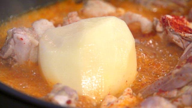 Spicy seasoned chicken and potatoes boiling in a pot