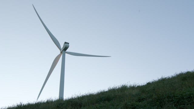 Wind Turbine on a Lush Hillside at Dusk