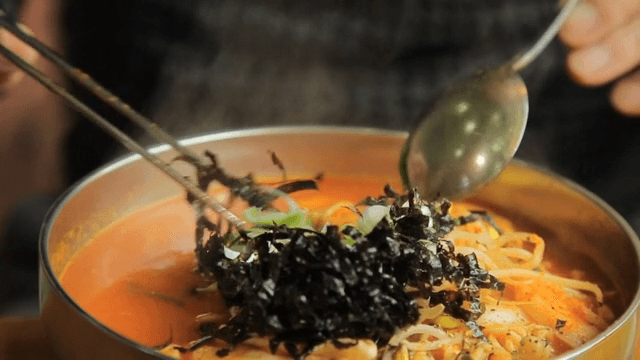 Spicy Korean rice cake ramen with bean sprouts and seaweed garnish