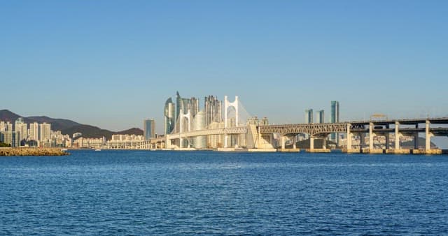 From day to night view of a bustling port city Busan with tall skyscrapers and Gwangan Bridge