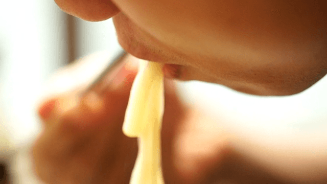 Person enjoying udon noodles with chopsticks