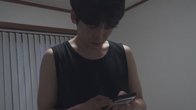 Young man intently looking at his smartphone in a dimly lit room