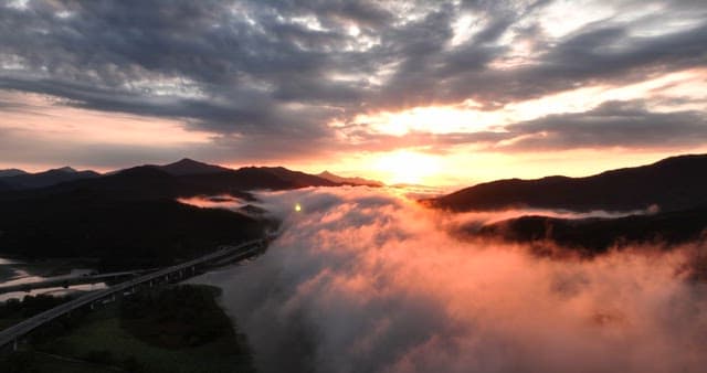 Sunset over mountains with misty clouds