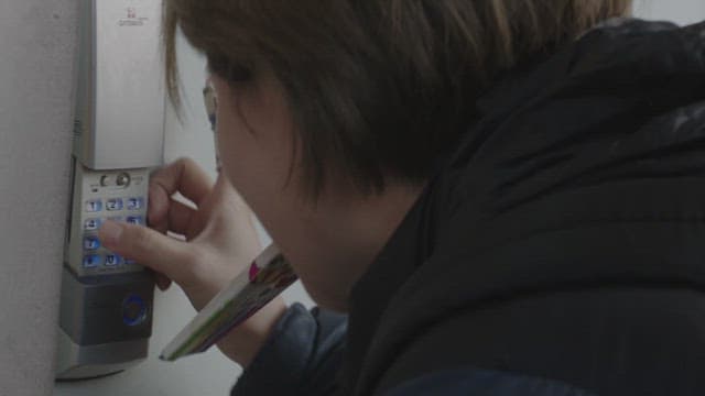 Woman pressing the buttons of keypad on front door lock