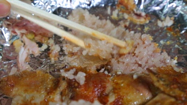 Holding the scorched rice in the foil with chopsticks
