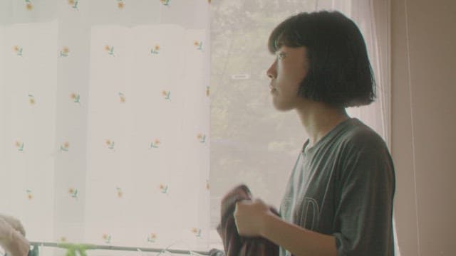 Woman standing by the window doing laundry in the morning