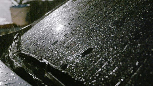Rain droplets on a car hood and windscreen at night