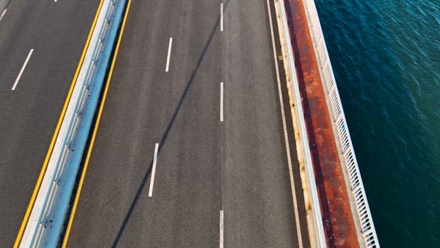 Vehicle Running on a Bridge with Flowing Blue Water