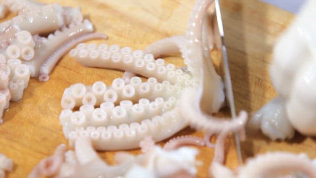 Cutting fresh octopus on a wooden board