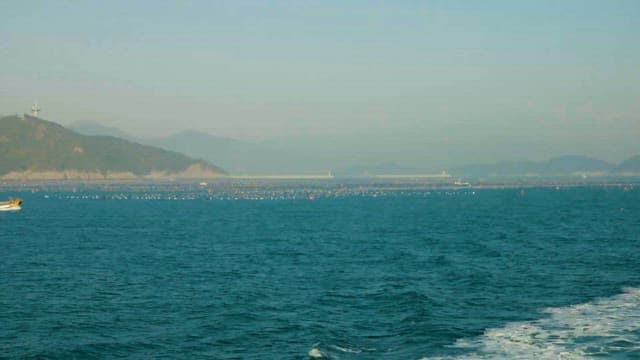 Serene Seascape of Farm with Passing Boat