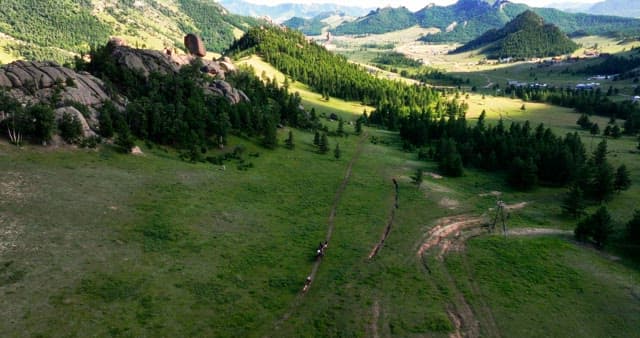 Horses riding through a scenic mountain valley